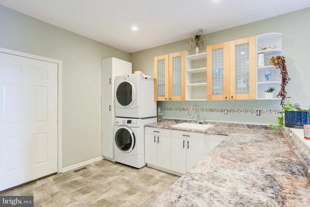 laundry room featuring stacked washer / drying machine and sink