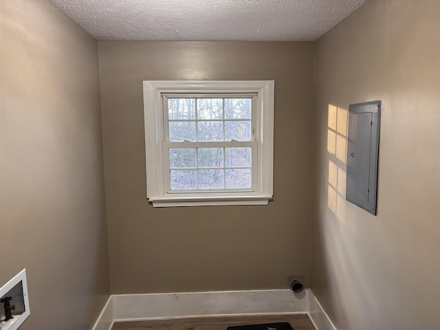 laundry room featuring a textured ceiling, laundry area, washer hookup, baseboards, and electric panel