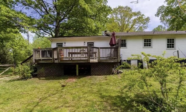 back of property featuring a wooden deck and a yard