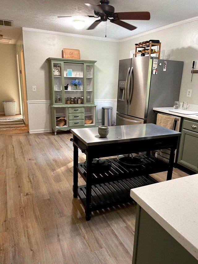 kitchen with crown molding, light hardwood / wood-style flooring, green cabinets, a textured ceiling, and stainless steel fridge with ice dispenser