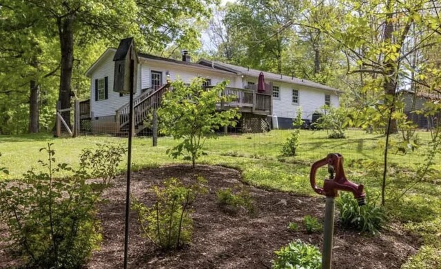 view of front of property featuring a front yard, a wooden deck, and stairs