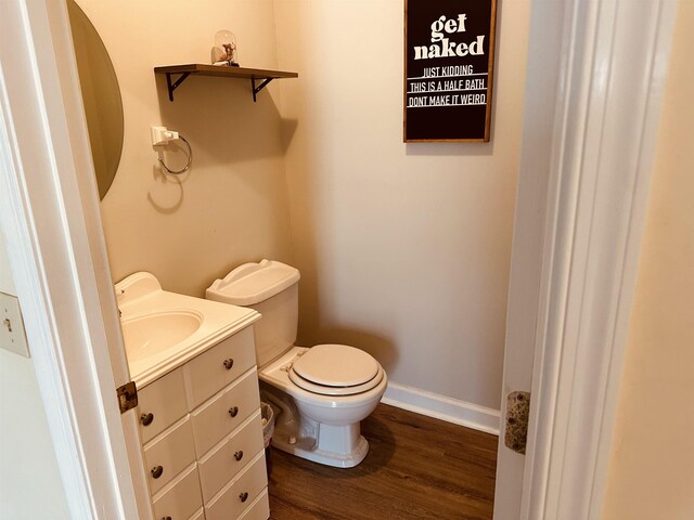 bathroom with toilet, baseboards, wood finished floors, and vanity