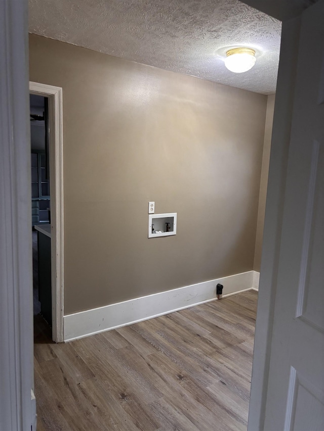 clothes washing area featuring a textured ceiling, laundry area, washer hookup, wood finished floors, and baseboards