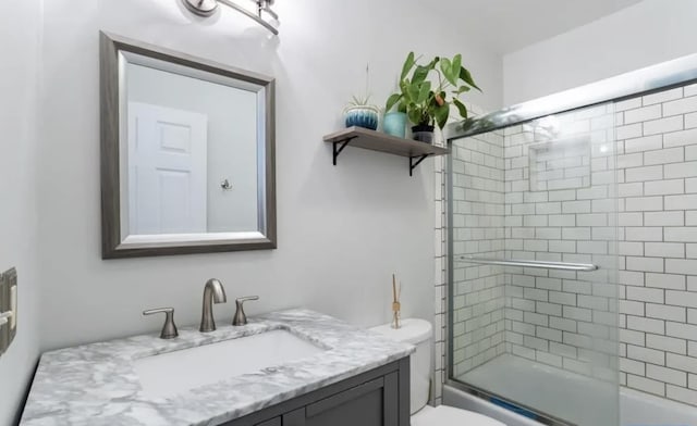 full bathroom with vanity, shower / bath combination with glass door, and toilet