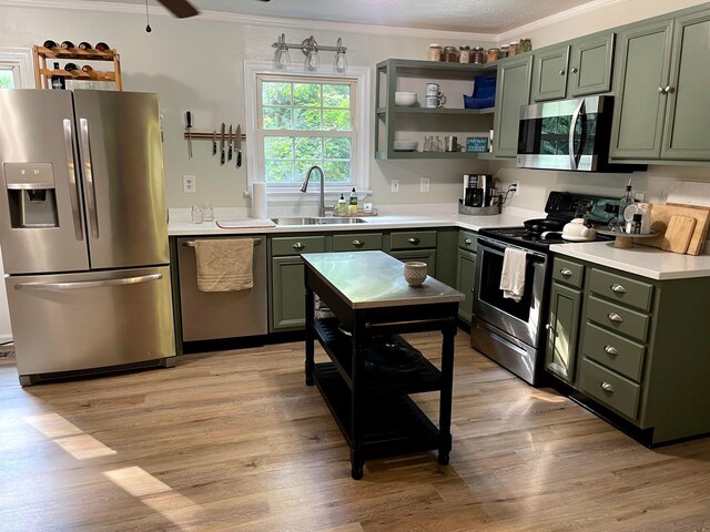 kitchen with sink, crown molding, light wood-type flooring, ceiling fan, and stainless steel appliances