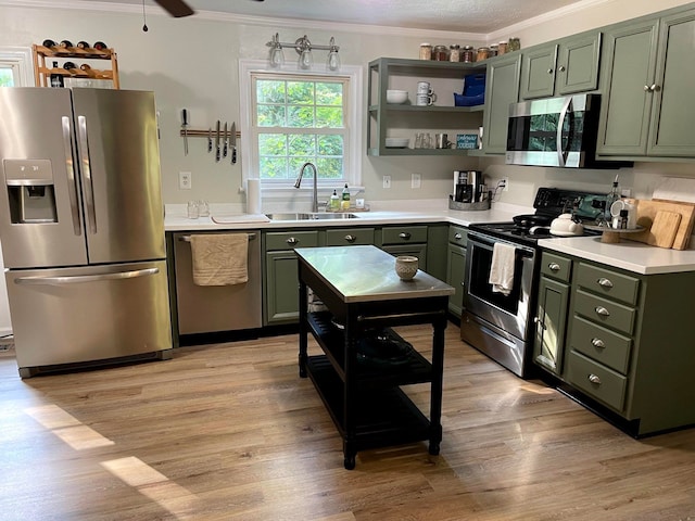 kitchen featuring appliances with stainless steel finishes, green cabinetry, a sink, and ornamental molding