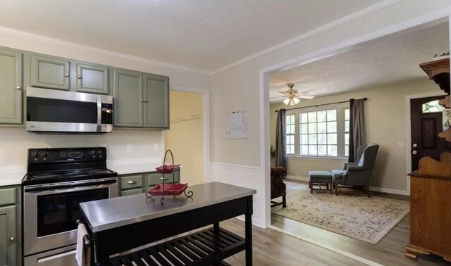 kitchen with stainless steel appliances, a ceiling fan, light countertops, and wood finished floors