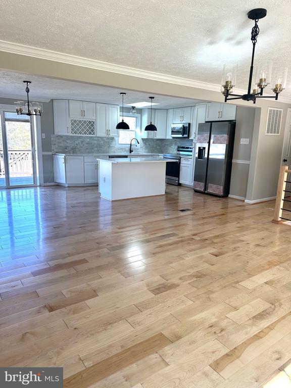 kitchen with an inviting chandelier, plenty of natural light, tasteful backsplash, and stainless steel appliances