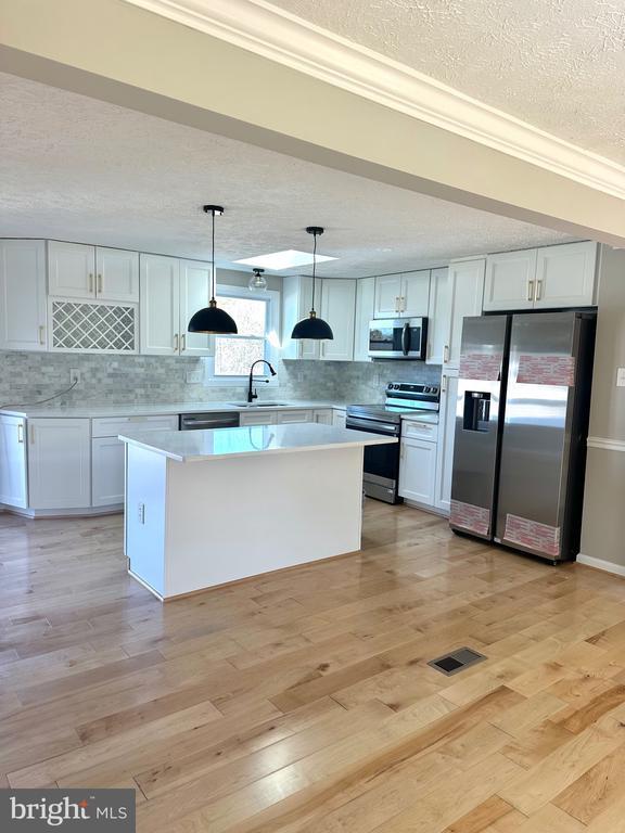 kitchen featuring appliances with stainless steel finishes, light countertops, light wood-style floors, and a sink