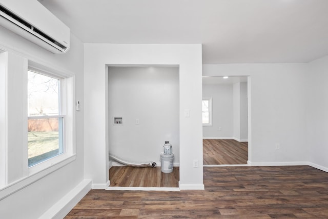 washroom with a wall mounted air conditioner, baseboards, and wood finished floors