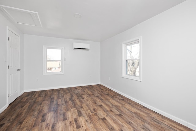 unfurnished room featuring a healthy amount of sunlight, baseboards, wood finished floors, and a wall mounted AC