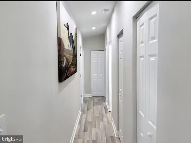 corridor featuring light wood finished floors and baseboards