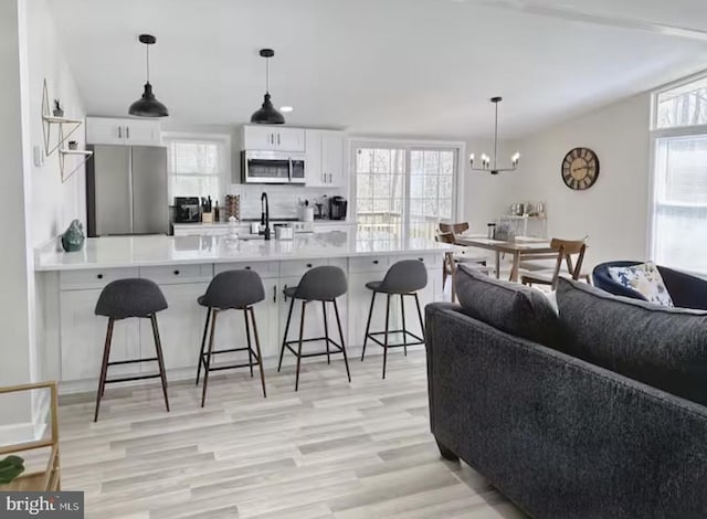 kitchen featuring appliances with stainless steel finishes, a wealth of natural light, white cabinetry, and a breakfast bar area