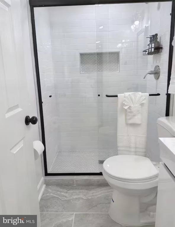 bathroom featuring a shower stall and toilet