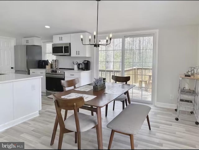 dining space with light wood-style flooring, baseboards, a notable chandelier, and recessed lighting