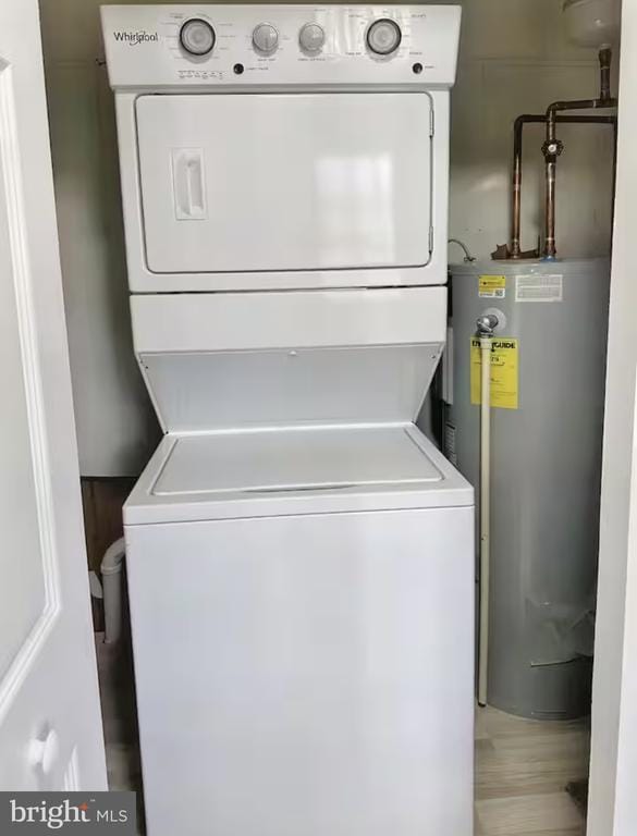 clothes washing area featuring laundry area, stacked washer / drying machine, and electric water heater