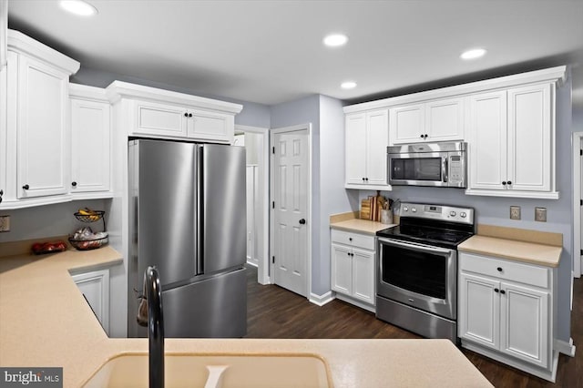 kitchen featuring light countertops, appliances with stainless steel finishes, white cabinets, and dark wood-style floors