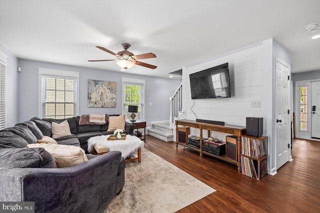living room with a ceiling fan, wood finished floors, a healthy amount of sunlight, and stairway