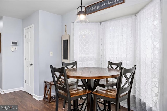 dining space with baseboards and dark wood-style flooring