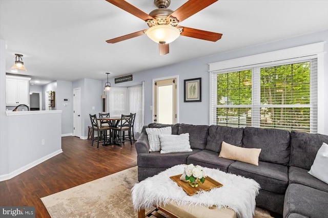 living room with baseboards, ceiling fan, and dark wood finished floors