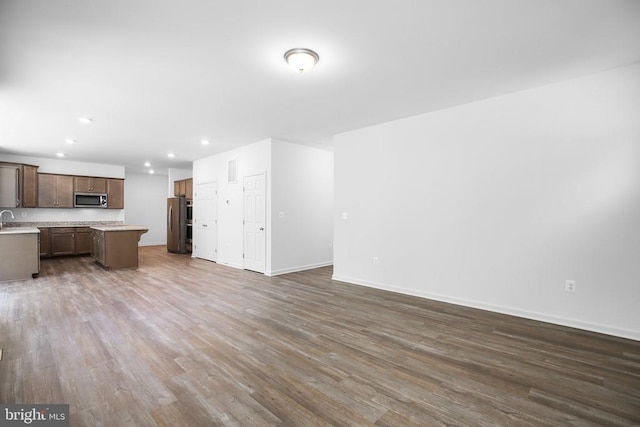 kitchen with appliances with stainless steel finishes, a center island, dark wood-type flooring, and sink