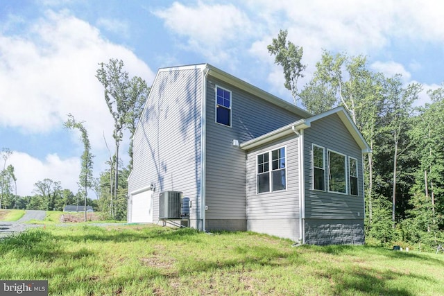 view of side of home with a yard, a garage, and central air condition unit