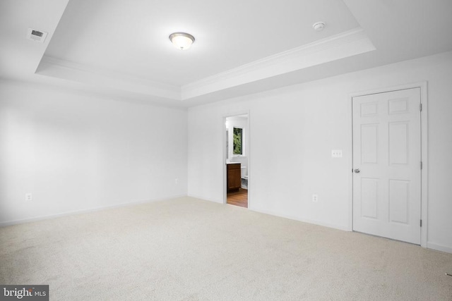 carpeted spare room featuring ornamental molding and a raised ceiling