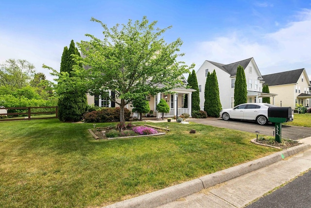 view of home's exterior featuring covered porch, a lawn, fence, and aphalt driveway