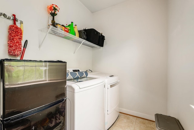 clothes washing area featuring laundry area, washer and clothes dryer, baseboards, and light tile patterned floors