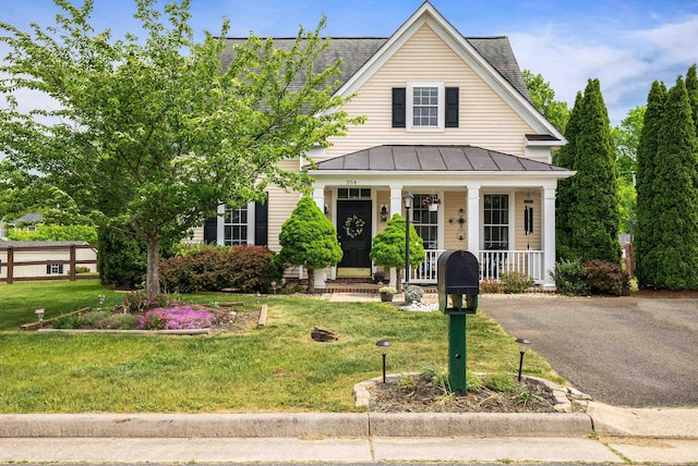 view of front of house with a front yard, roof with shingles, a standing seam roof, metal roof, and a porch