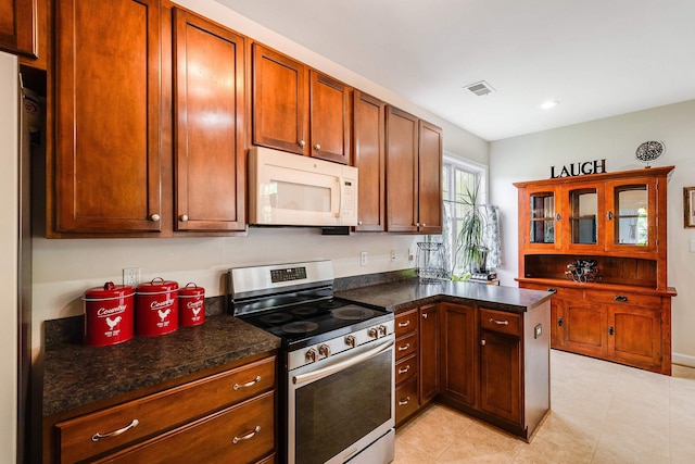kitchen with visible vents, electric range, white microwave, and dark countertops