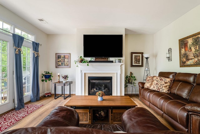 living room with baseboards, a glass covered fireplace, wood finished floors, and visible vents