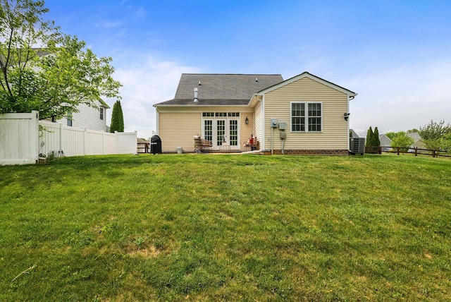 rear view of property with a lawn, fence, and french doors