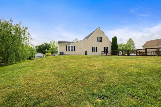 rear view of property featuring fence, a yard, and cooling unit