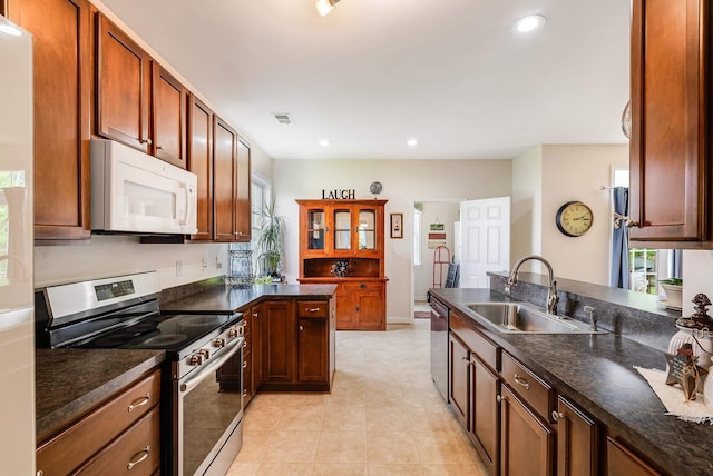 kitchen featuring a sink, a peninsula, dark countertops, and stainless steel appliances