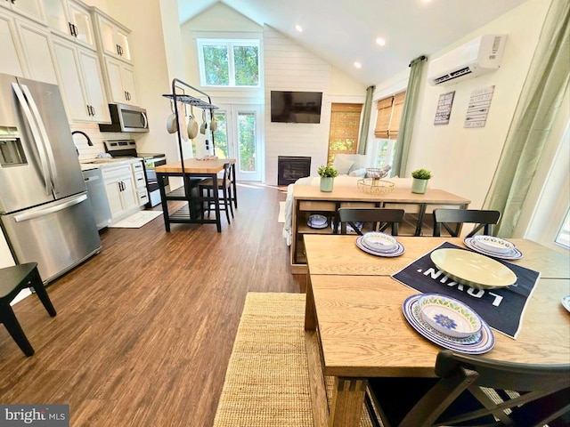 kitchen featuring a wall mounted air conditioner, a large fireplace, dark hardwood / wood-style flooring, stainless steel appliances, and white cabinets