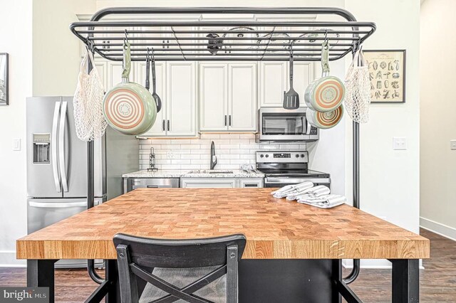 kitchen featuring tasteful backsplash, sink, a breakfast bar area, stainless steel appliances, and dark wood-type flooring