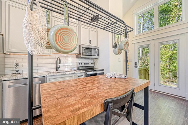 kitchen featuring sink, dark wood-type flooring, appliances with stainless steel finishes, tasteful backsplash, and light stone countertops