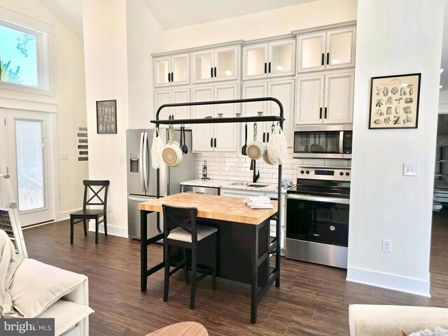 kitchen with butcher block counters, stainless steel appliances, white cabinets, a kitchen island, and decorative backsplash