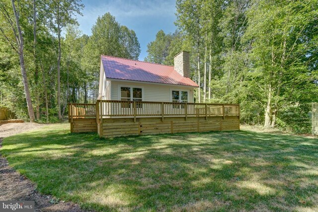 rear view of house featuring a wooden deck and a lawn