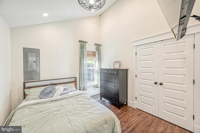 bedroom featuring dark hardwood / wood-style flooring, electric panel, vaulted ceiling, and a closet