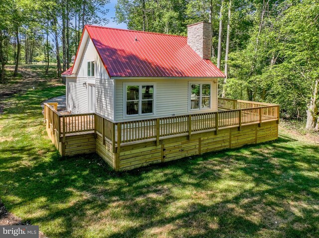 rear view of house featuring a wooden deck and a yard