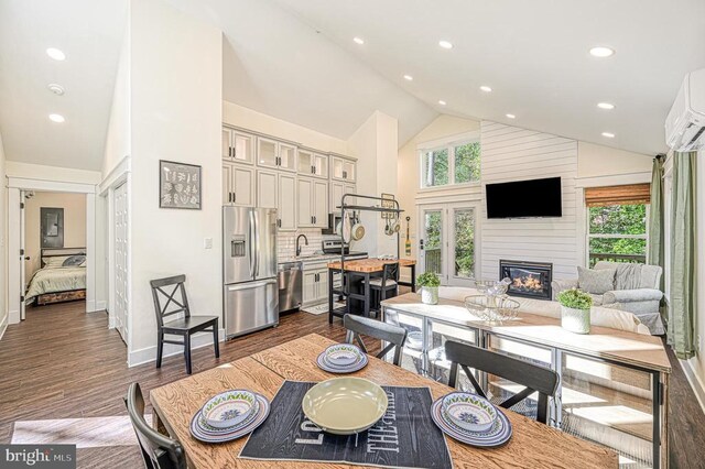 dining room with sink, a fireplace, dark hardwood / wood-style flooring, and high vaulted ceiling