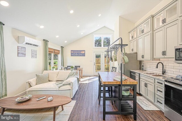 kitchen with an AC wall unit, sink, a wealth of natural light, and appliances with stainless steel finishes