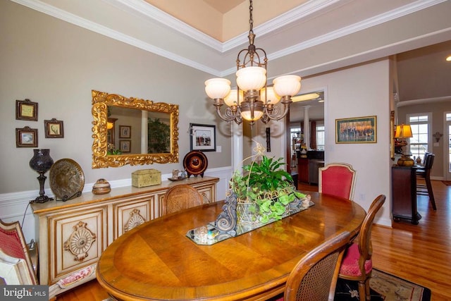 dining room with a notable chandelier, wood finished floors, and ornamental molding