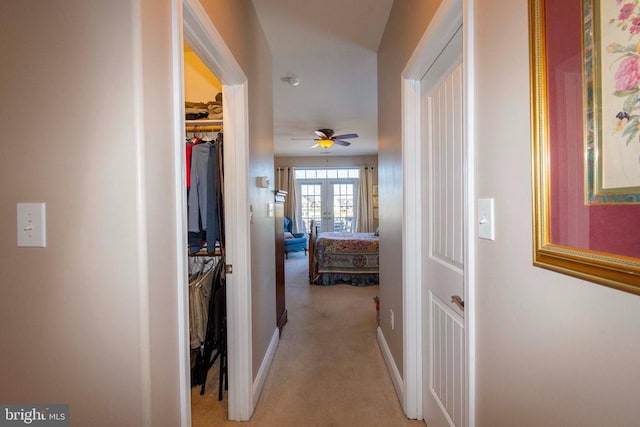 corridor with baseboards and light carpet