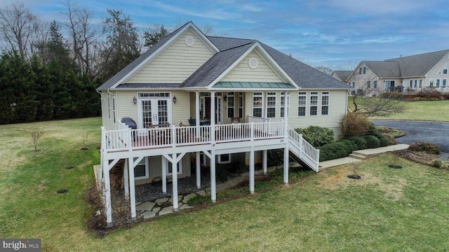 rear view of property featuring a shingled roof, stairs, and a lawn