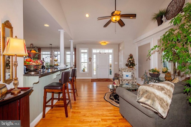 living room with a ceiling fan, decorative columns, recessed lighting, vaulted ceiling, and light wood-style floors