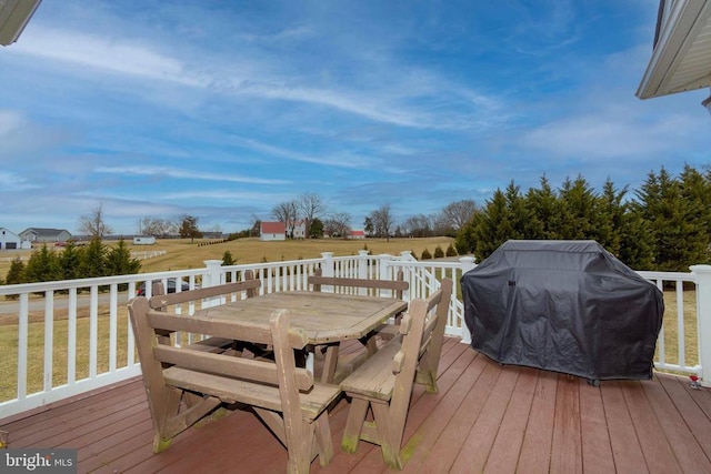 wooden terrace featuring outdoor dining space, a yard, and a grill