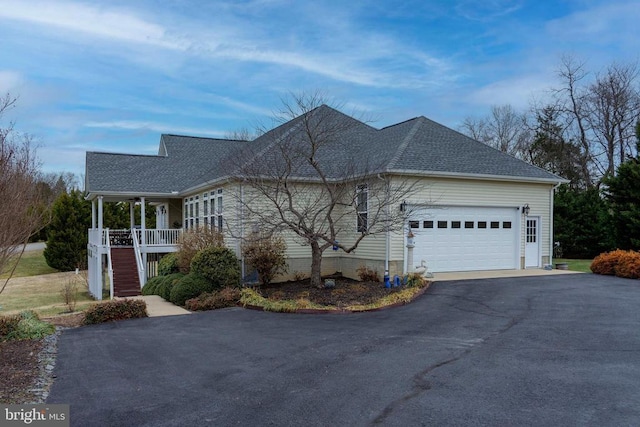 view of home's exterior featuring aphalt driveway, a porch, stairway, a shingled roof, and a garage